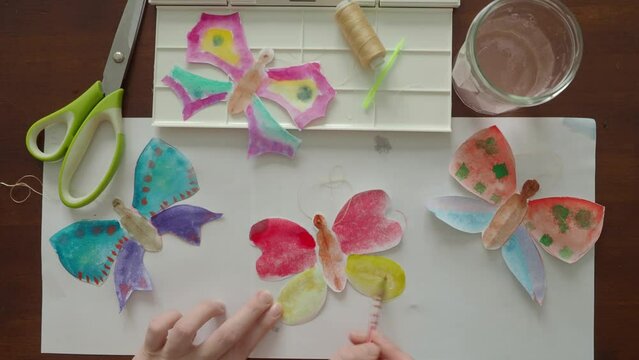 Coloring paper dolls of butterflies with watercolors for speech therapy classes with a child. Breathing exercises and early speech development. Making crafts for kindergarten