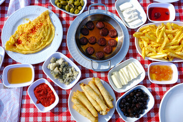 Turkish breakfast, traditional Turkish breakfast, cheese, honey, jam, olives, sauce, french fries,spring roll, fried sausage. Top view.