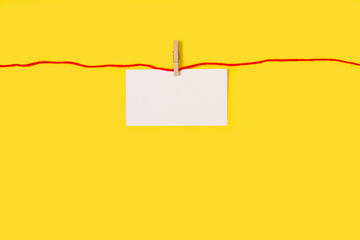 Cartel en blanco colgando sobre un fodno amarillo liso y aislado. Vista de frente. Copy space