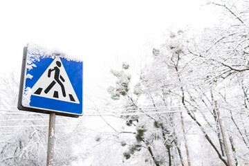 Frozen pedestrian sign covered in snow on a frosty snowy day.