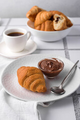 coffee and croissants, chocolate cream, french press and newspaper, book on the table, morning breakfast 