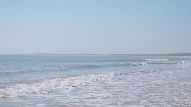Slow motion video of Small ocean waves breaking on sandy beach at Mandvi beach, Kutch, India. Tropical beach Natural background for summer vacation.  Travel and holiday at beach