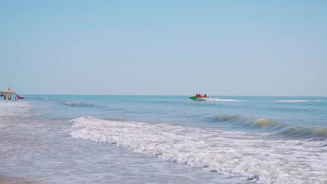 View of speed boat in beach with blue sky. Blue water of Mandvi beach, Gujarat, India. Travel destination in summer. Adventure activity at beach. People enjoying holiday