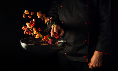 Cooking vegetables by chef hands on dark background copy space. Food concept. Vegetable menu for the hotel - obrazy, fototapety, plakaty