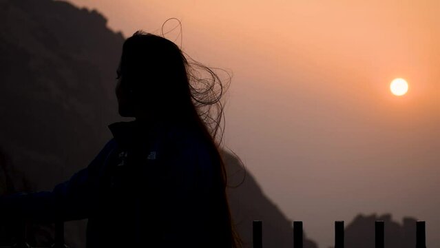 Silhouette of happy Indian woman enjoying sunrise at mountain. At Girnar hills, Gujarat, India. People and sunrise sky. Travel and holidays concept