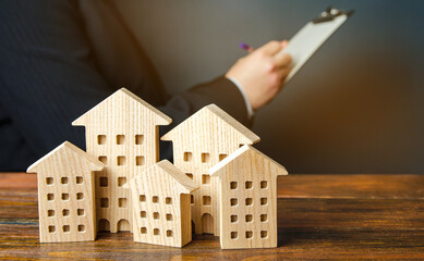 Wooden houses and a businessman in the background. Real estate market analysis concept. Affordable...