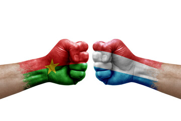 Two hands punch to each others on white background. Country flags painted fists, conflict crisis concept between burkina faso and luxembourg