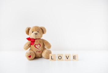 Cute toy teddy bear with a heart isolated on a white background. Love lettering, Valentine's Day holiday concept.