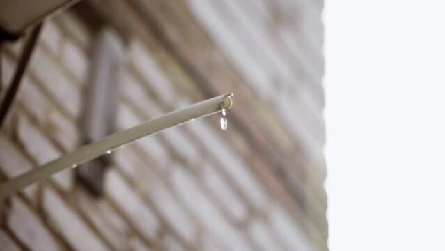 Drops of water falling from the hose from the air conditioner. Plastic drain pipe from air conditioning outside building. Air conditioning