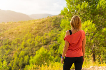 hiker woman observing the landscape of a Mediterranean forest in a summer sunset