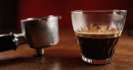 Glass cup of espresso coffee with crema on wooden table