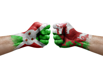 Two hands punch to each others on white background. Country flags painted fists, conflict crisis concept between burundi and wales