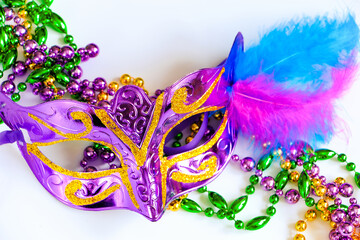 Purple carnival mask with feathers and colorful beads close-up. Mardi Gras or Fat Tuesday symbol.