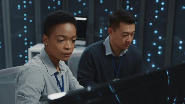 Professional smart IT management team working on software development cloud computing research server data in computer office data center room. Mulri-ethnic people.