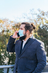 Young business man talking mobile with face mask