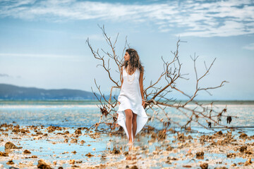 Beautiful young stylish woman in white dress on the beach