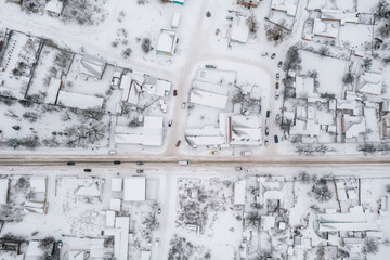 Aerial view of a small village in winter. Rural road passing between snow-covered houses. Winter landscape