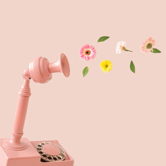 Pink retro telephone with colorful spring flowers against pastel pink background. Telecommunication...