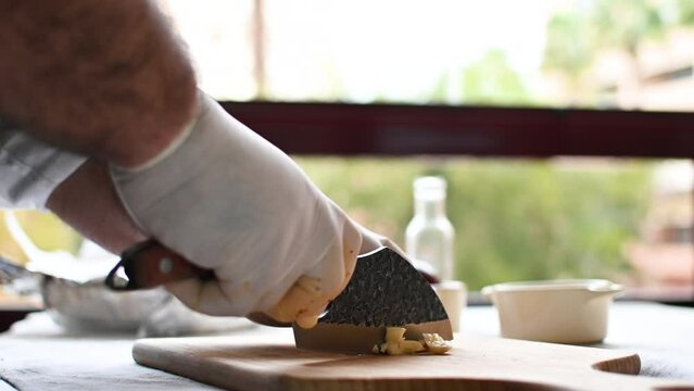 Chef cuts garlic on a cutting board with a knife