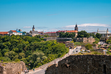 Naklejka premium Kyiv, Ukraine. July 20, 2021. Ancient ruined structure, green trees in forest, Church and other city buildings with cars moving on road