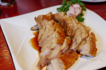 Selective focus, sliced crispy belly pork served on white plate.