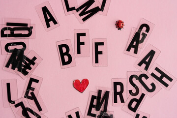 letras formando la palabra BFF sobre fondo rosado y letras desordenadas debajo