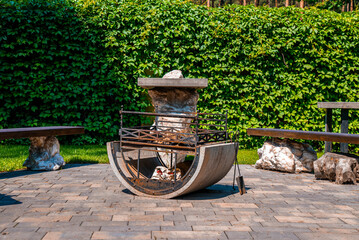 Sunny backyard with iron fire pit and benches on stone pavement, Garden rest area with fire pit...