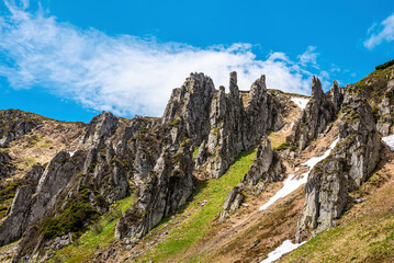 Rocky cliff and peak of mountain with steep slope and moss against cloudy sky. Beautiful view of nature