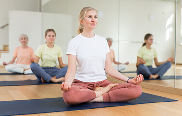 Fototapeta na wymiar Closeup of positive woman practice yoga lotus pose to meditation in modern studio