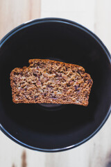 slice of vegan banana bread with cinnamon in black bowl on wooden table, healthy plant-based food
