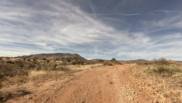 Sandy road stretching along the desert with blue clear sky above. Beautiful natural wilderness during a road trip in the United States. High quality 4k footage
