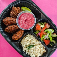 Falafel to go dish top view and pink backgroud