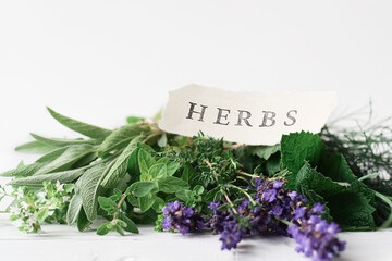 Variety of fresh herbs on a white table with a label