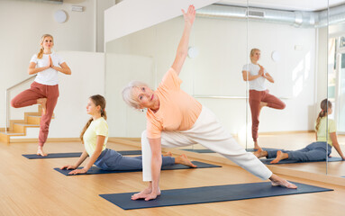 Naklejka na ściany i meble Women exercising yoga poses in fitness center. Extended triangle pose
