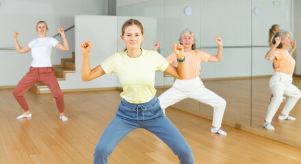 Fototapeta na wymiar Young positive teenager girl dancing during group class in dance center