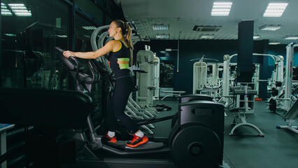 Fit Athletic Woman Exercising on an Elliptical Machine. Muscular Women Activity Training in Modern Gym. Sports People Workout in an Elliptic Walking Trainer Fitness. Exercise Slow Motion