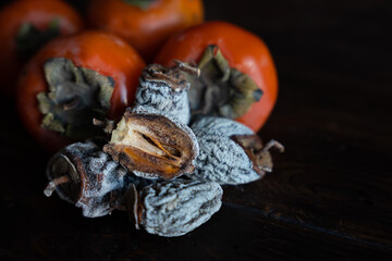 Fototapeta na wymiar Dried persimmon and fresh persimmon on a wooden background. Healthy diet. Healthy diet