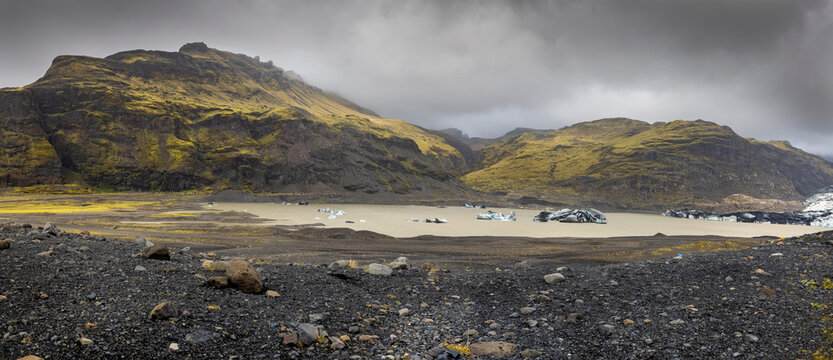 Panoramic view of hills around Svinafellsjokull glacier in southern Iceland, floating ice in the lake, overcast sky .