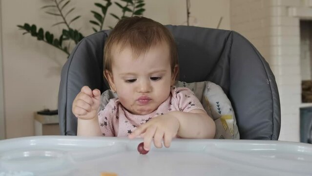 The Human Hand Throwing A Berry On The Baby's Table, Which He Takes And Puts In His Mouth. Delicious Food.