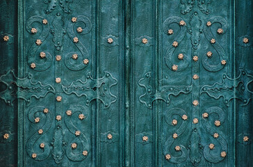 An old green metal door with an openwork ornate pattern. Vintage background closeup. Medieval forging technologies.