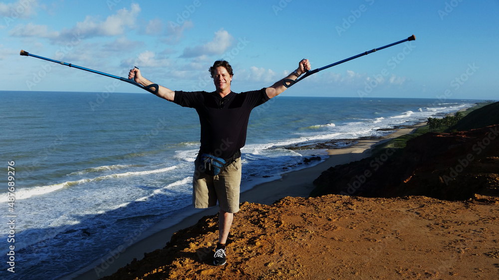 Wall mural people with physical disabilities. disabled man with open arms on the beach.