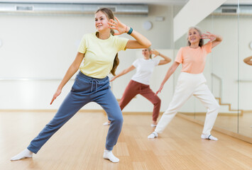 Fototapeta na wymiar Teenage girl performing dance during group training in studio.