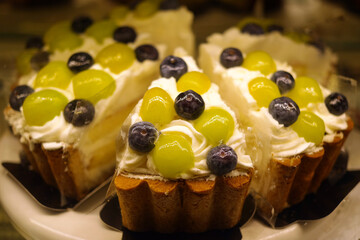 Sculpture cakes decorated with green grapes and blueberries are on display.