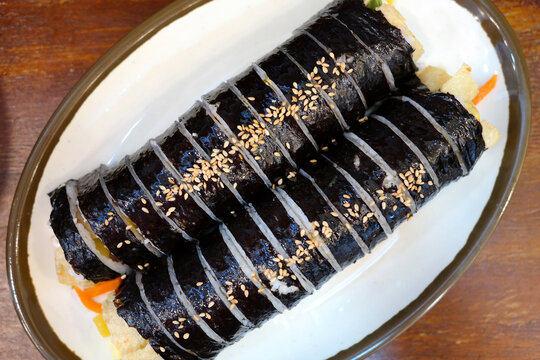This is the appearance of seeing kimbap on a white plate from above.