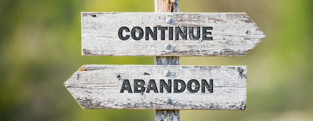 opposite signs on wooden signpost with the text quote continue abandon engraved. Web banner format.