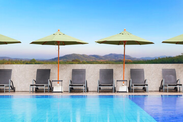 Sun bed beside the swimming pool with sky