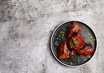 Roasted chicken wings with beetroot risotto on a round plate on a dark gray background. Top view, flat lay