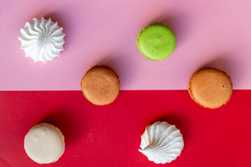 Top view of colorful macaron or macaroon on red pink background. selective focus. Flat lay with Almond cookies.Variety of macarons pastry and homemade white merengue.