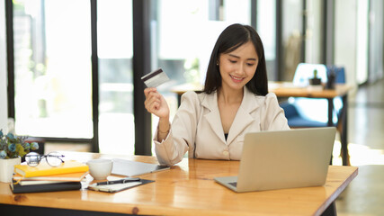 Woman searching interested online product on laptop and pay with credit card.