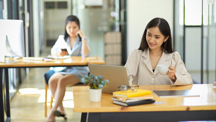 Business employee working on laptop computer and sipping coffee